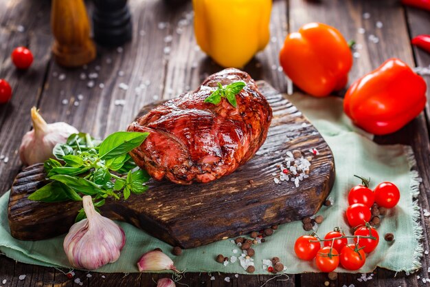 Foto carne affumicata o maiale con lardo, fette, pomodorini, erbe e spezie, su un legno nero, taglio