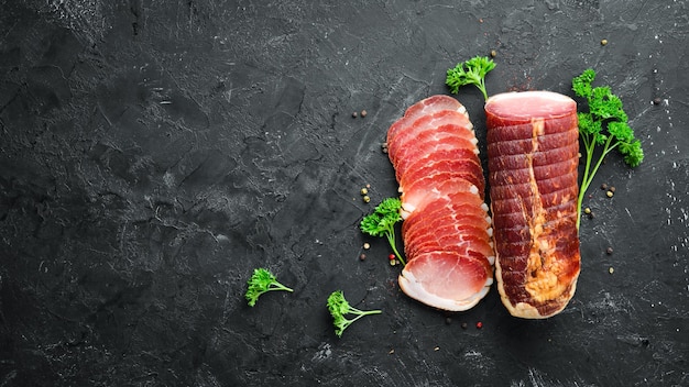 Smoked meat with spices and herbs On a black wooden background Top view Free space for your text