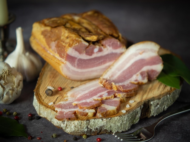 Smoked pork belly on a cutting board against a dark background