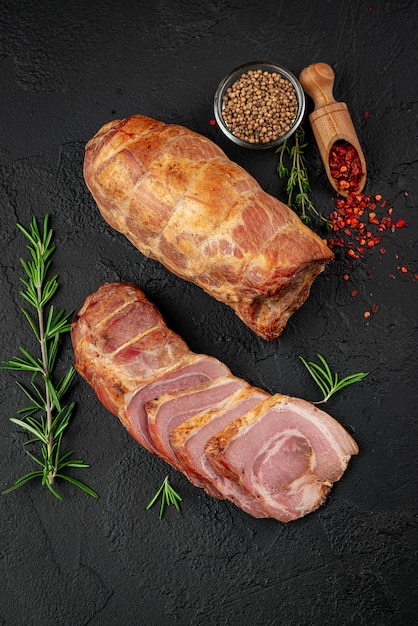 Smoked pork roll with spices on a dark background