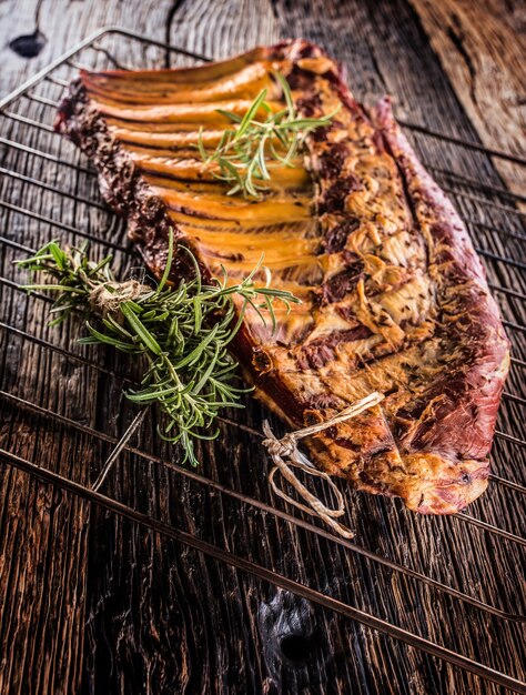 Smoked raw pork ribs and rosemary herbs on wooden board.