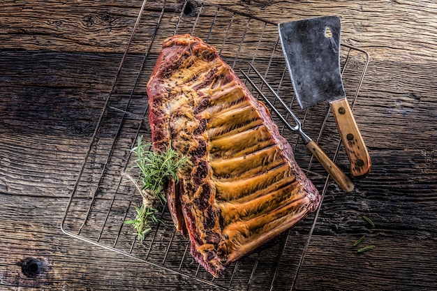 Smoked raw pork ribs and rosemary herbs on wooden board.