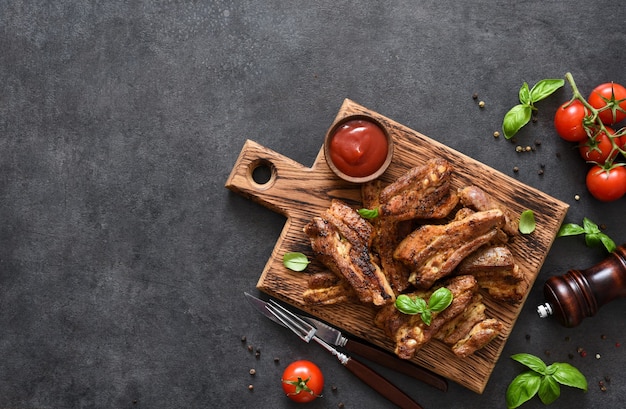 Smoked ribs, grilled on a wood board with sauce and basil on a stone table