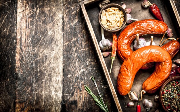 Smoked salami with spices and garlic. On a wooden background.