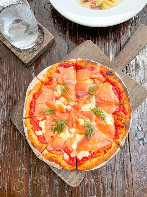 Foto pizza al salmone affumicato su vassoio di legno