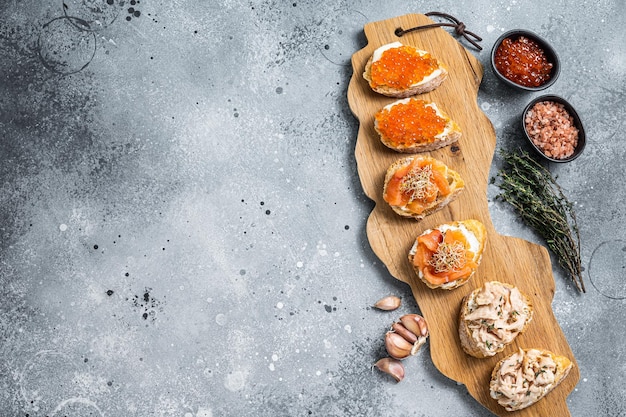 Smoked salmon and red caviar  toasts appetizer with cream cheese. Gray background. Top view. Copy space.