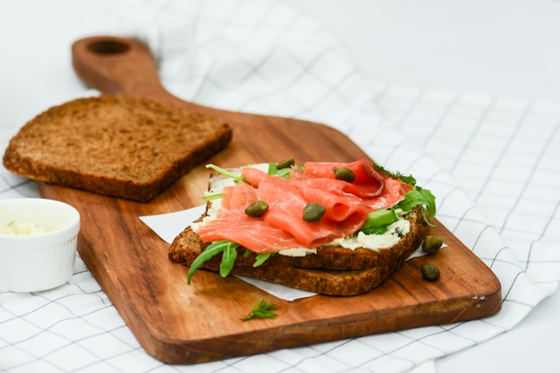 Smoked salmon sandwich with cheese, pistachio and salad leaves, brown breads