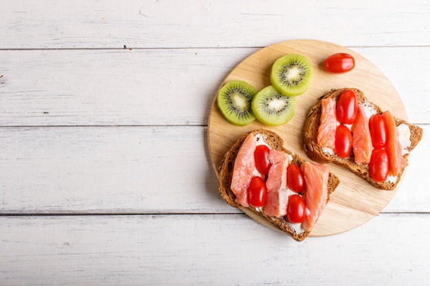 Foto panini al salmone affumicato con burro e pomodori ciliegia su bianco