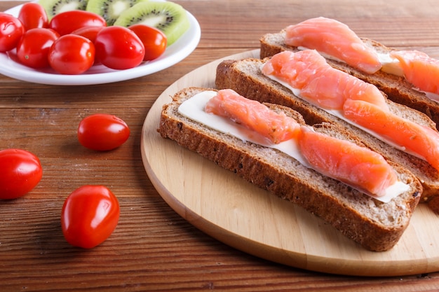 Smoked salmon sandwiches with butter on wooden background