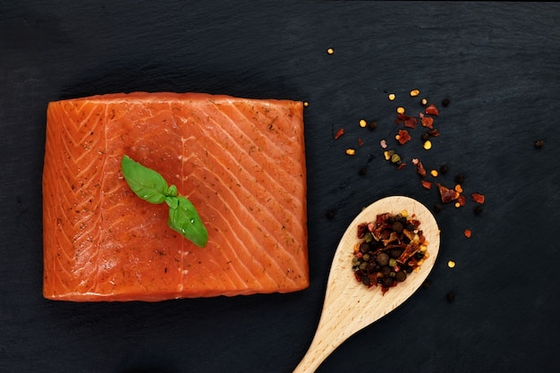 Smoked Salmon and spices in wood spoon on black slate plate