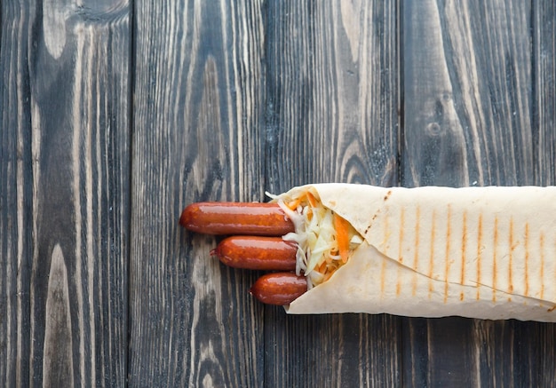 Smoked sausage in pita bread on a dark wooden backgroundphoto with copy space