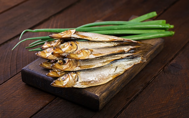 Smoked sprat and green onion  on a cutting board