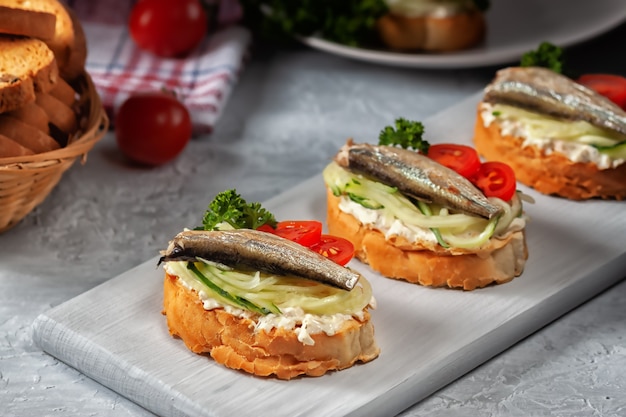 Smoked sprat sandwich - fish, fresh cucumber and tomato. sprat sandwiches on toasted slices of bread