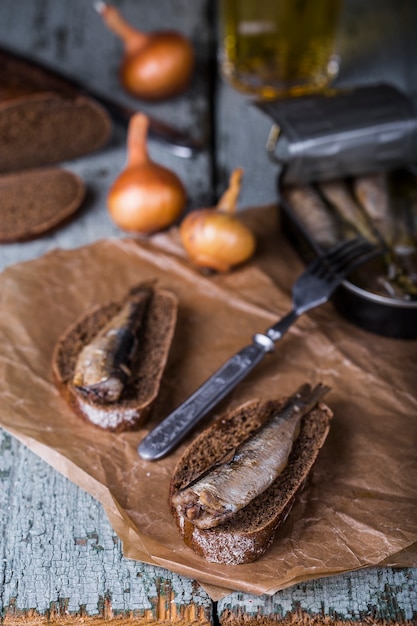 Smoked sprats with rye bread on wooden background