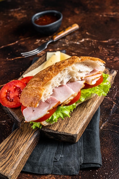 Smoked turkey sandwich with ham cheese tomato and Lettuce Dark background Top view