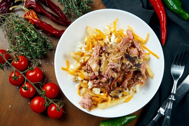 Smoker beef brisket with peanut sauce and a side dish of french fries in a white bowl on a wooden table. Baked beef. BBQ