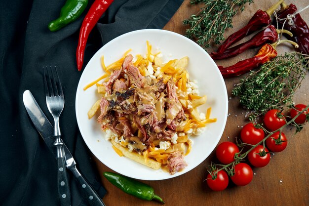 Smoker beef brisket with peanut sauce and a side dish of french fries in a white bowl on a wooden table. Baked beef. BBQ