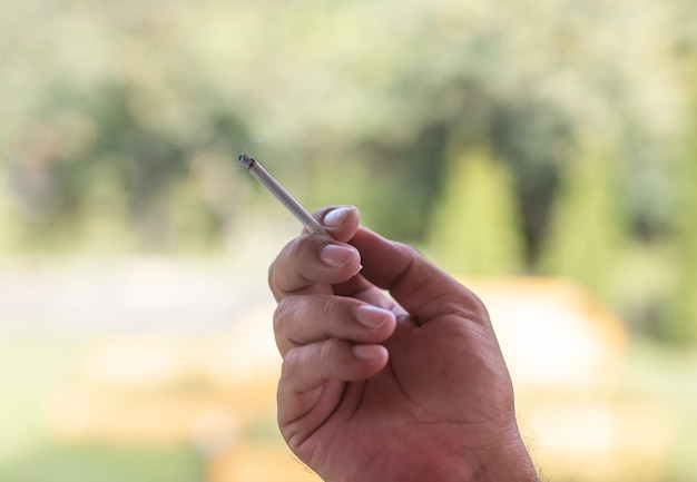 Smoker hand with cigarette outdoors in nature