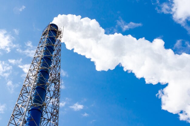 Smokestack and steam on blue sky