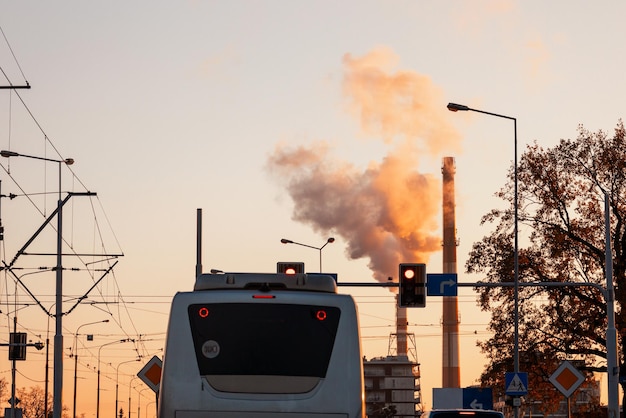 Smoking chimneys of a factory in the city against the backdrop of a pinkyellow sunset