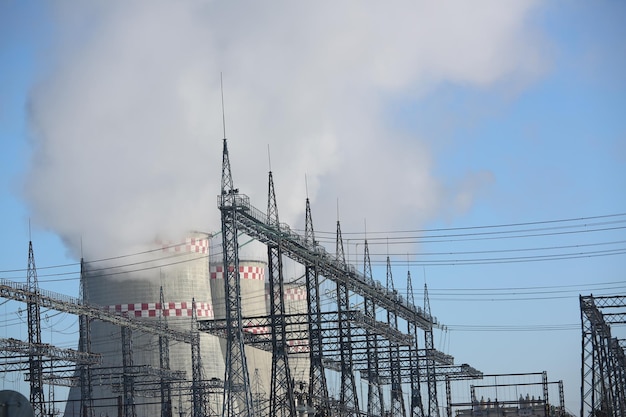 Smoking chimneys of various sizes of thermal power plant against blue sky