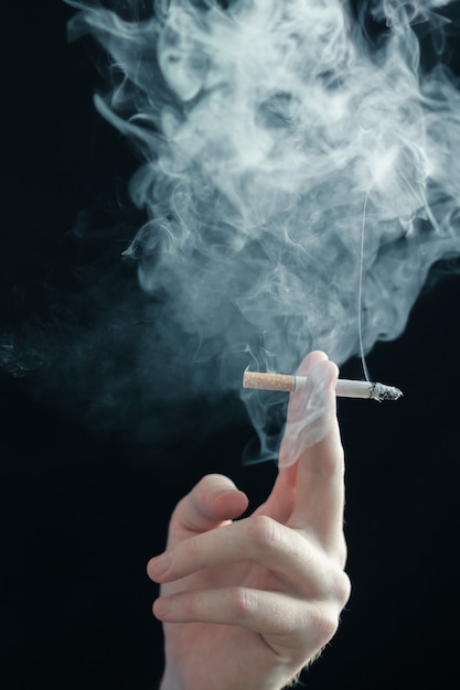 smoking cigarette in hand on black surface
