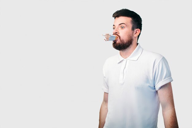 Smoking concept. The bearded dark-haired guy holds a lot of cigarettes in his mouth.