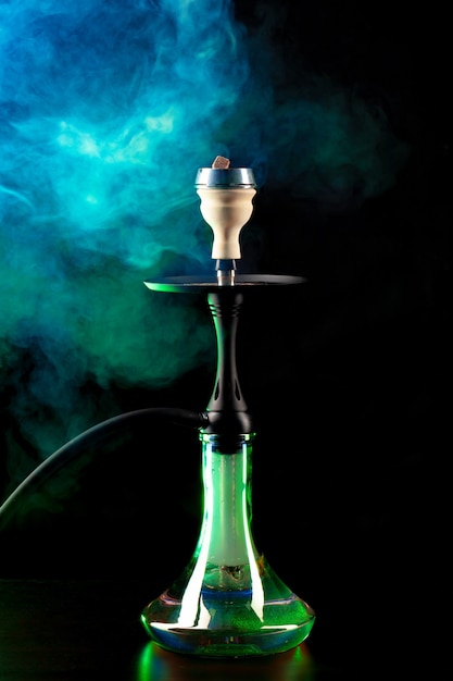 Smoking hookah on black background with color fog copy space