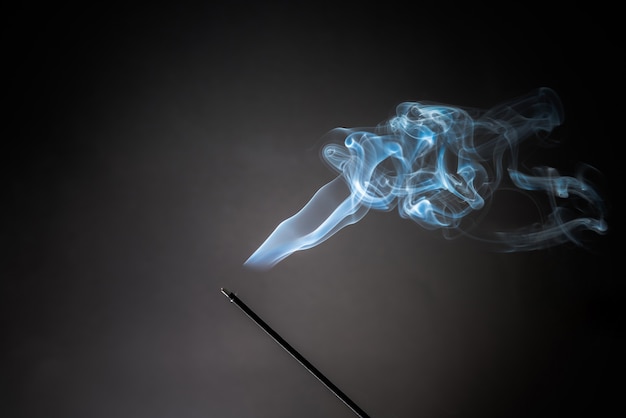 Smoking incense stick with relaxing smoke rising up.