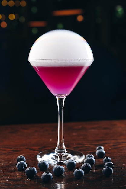 Foto fumare bicchiere da martini con bevanda viola cocktail con mirtilli