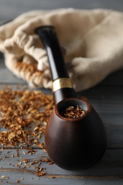 Smoking pipe tobacco and sack on wooden background