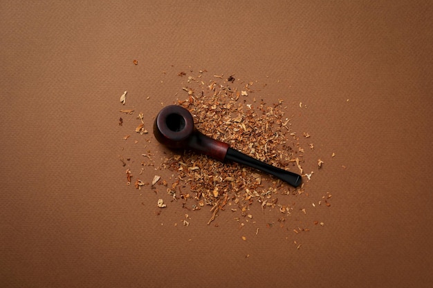 Smoking pipe with tobacco on brown background