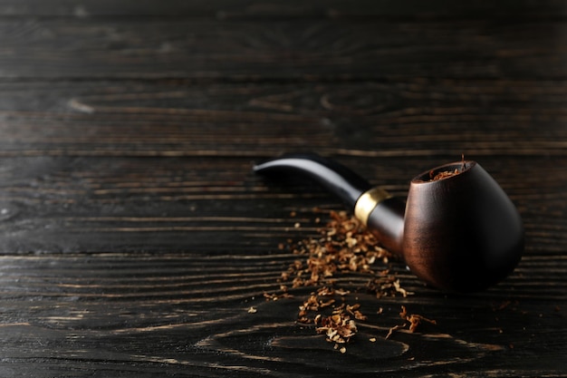 Smoking pipe with tobacco on wooden background