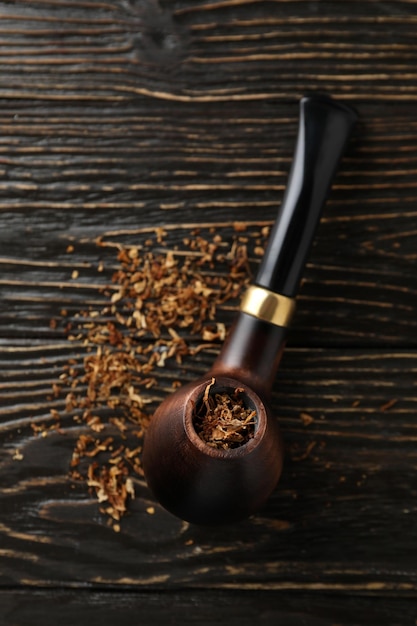 Smoking pipe with tobacco on wooden background