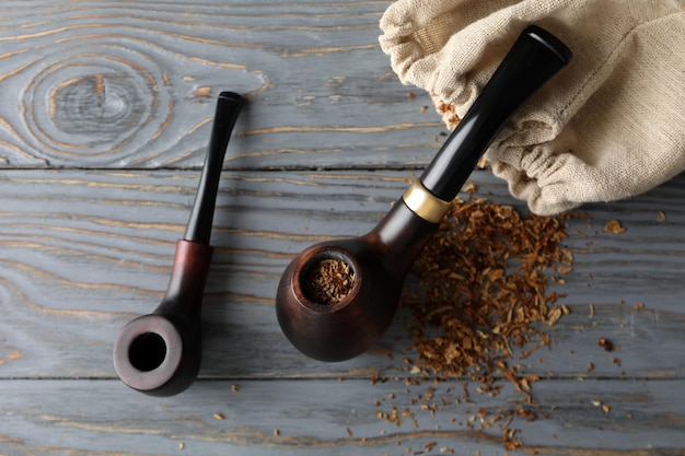 Smoking pipes tobacco and sack on wooden background