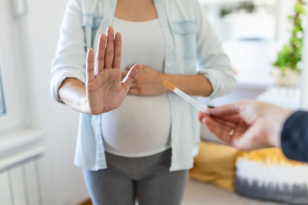 Smoking and pregnancy. pregnant girl refusing to take cigarette
gesturing stop. pregnant woman with belly refuses passive smoking.
the concept of the rejection of bad habits