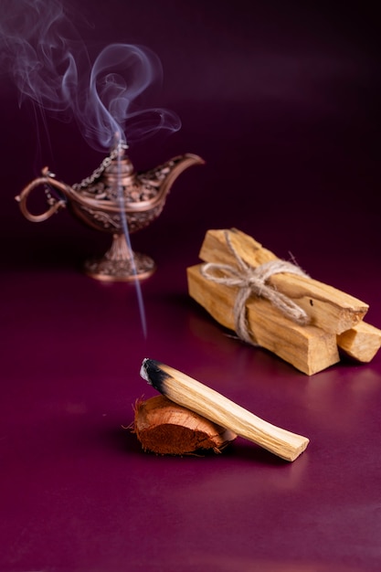 Foto un bastoncino fumante di un albero di palo santo con una lampada aromatica orientale su uno sfondo scuro