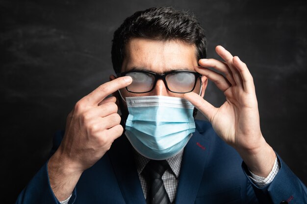 Smoky glasses and a man trying to clean his glasses on a dark surface