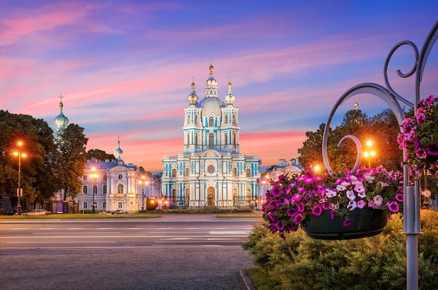 Foto smolny-kathedraal in sint-petersburg op een achtergrond van een roze lucht en kleurrijke bloemen van petunia