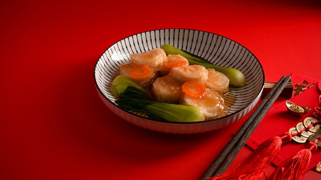 Smoor tahoe met oestersaus en groente op een bord en eetstokjes op een rode eettafel