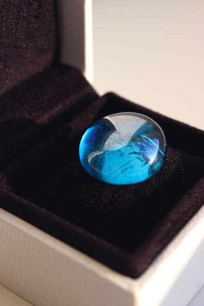 Гладкий голубой стеклянный камень на черной бархатной подушке в элегантной подарочной коробке подробное стоковое фото