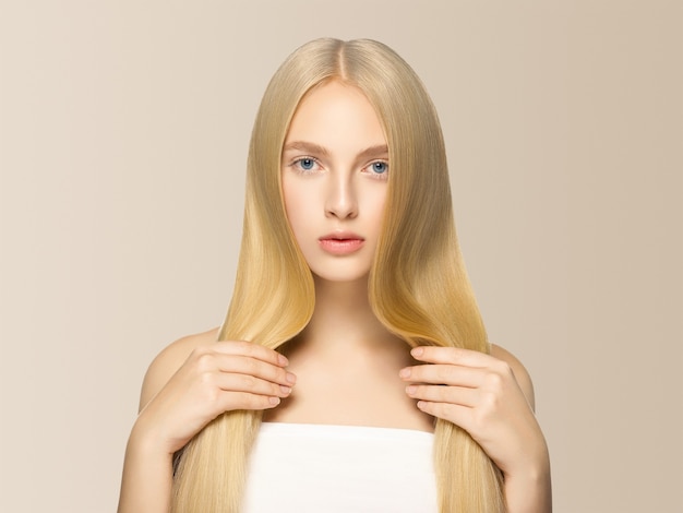 Smooth long blond hair woman natural make up healthy skin. On beige.