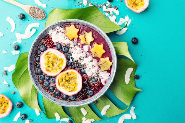 Smoothie acai bowl served in bowl on blue table 