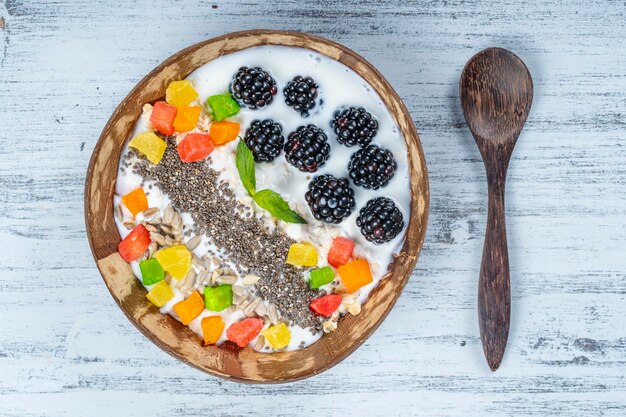 Smoothie in coconut bowl with blackberries oatmeal sunflower seeds and chia seeds for breakfast close up The concept of healthy eating superfood Top view