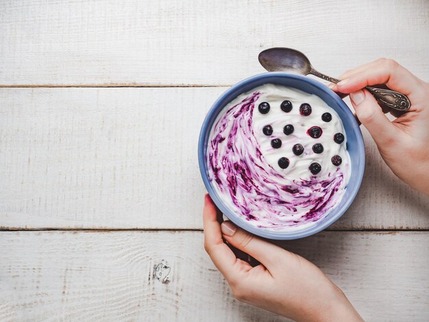 Smoothie, fresh berries, vintage bowl and women's hands