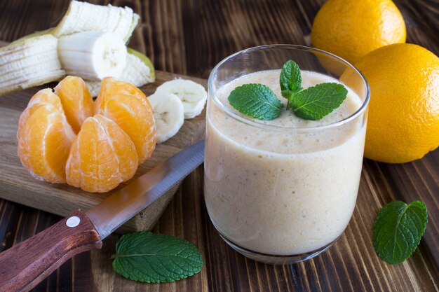 Smoothie from banana, mandarin and ingredients on the wooden background