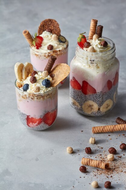 Smoothie in glasses with fruits strawberry, banana, blueberry, oat flakes and chia