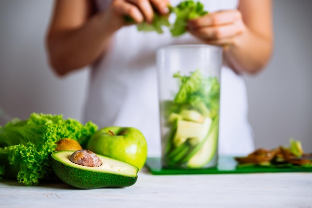 Smoothie ingredients in front. woman making smoothie on background. health food concept