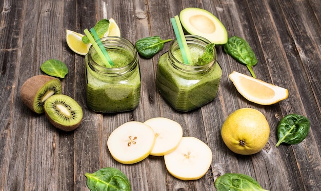 Smoothie met avocado, spinazie, limoen, kiwi en peer in een pot op verweerde houten achtergrond