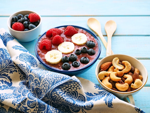 Smoothie met banaan, framboos, bosbes en noten op blauwe houten tafel